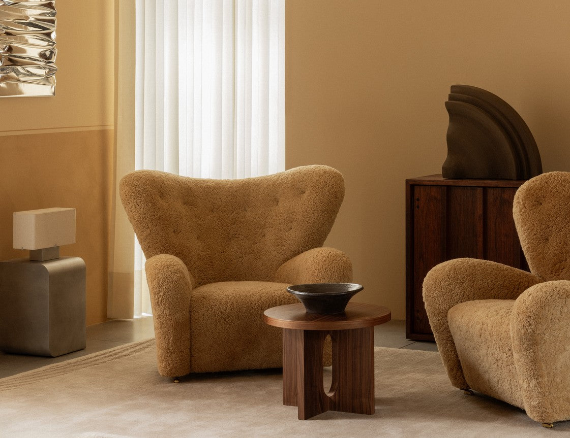 Pair of camel-colored boucle lounge chairs with rounded shapes around a walnut