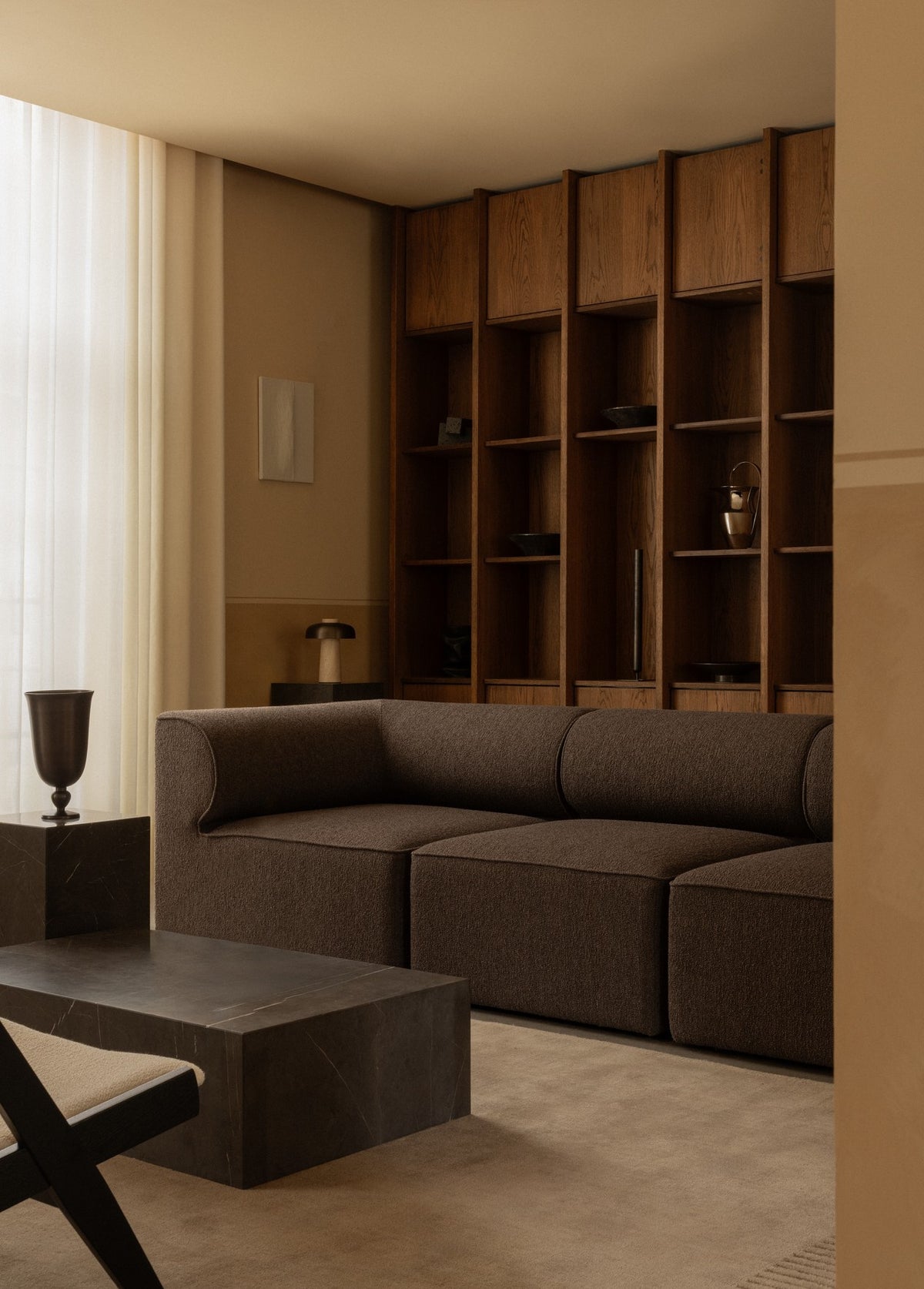 Brown modular fabric sofa in front of tall oak shelving, marble low