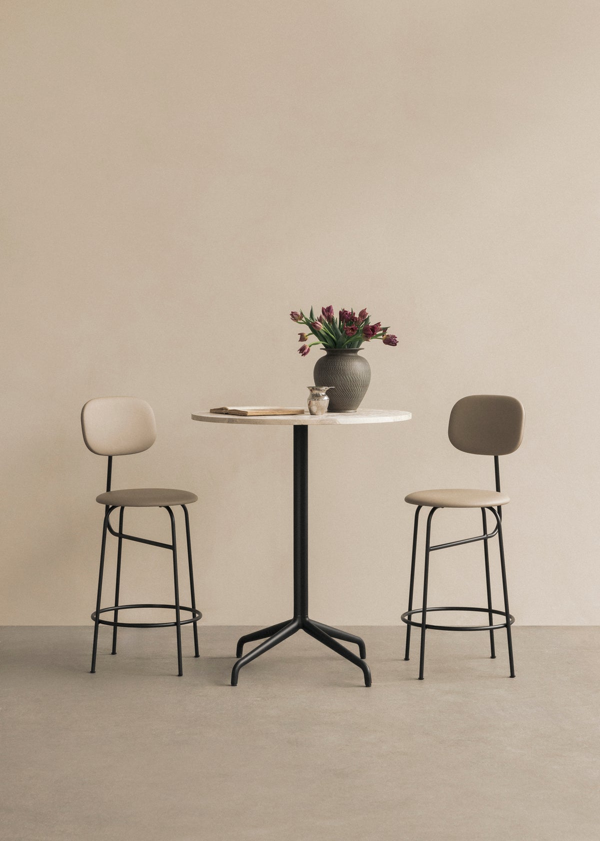 Round marble-top bistro table with black metal pedestal, two beige cushioned bar