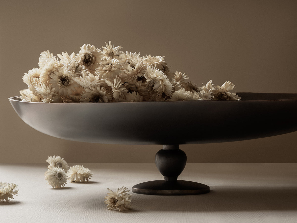 Matte black pedestal bowl filled with cream dried strawflowers, few blossoms sca