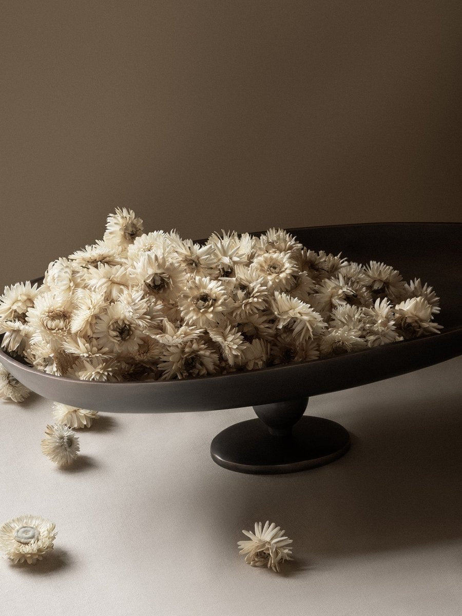 A close-up shot of the Pavot Centerpiece, a dark pedestal bowl, overflowing