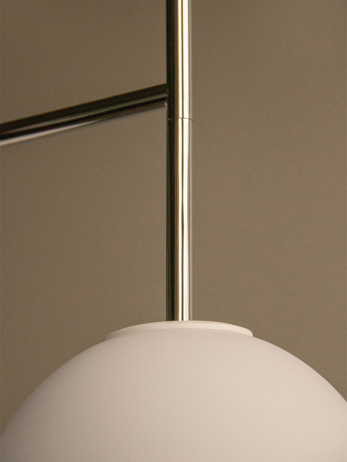 Close-up of a matte white spherical pendant lamp with a polished brass