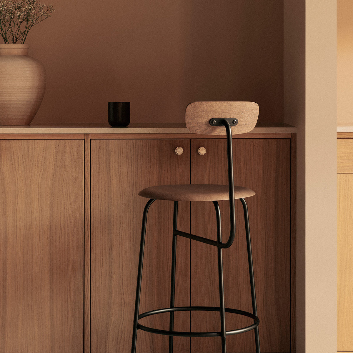 Dark wood bar chair with slender black metal frame positioned against a