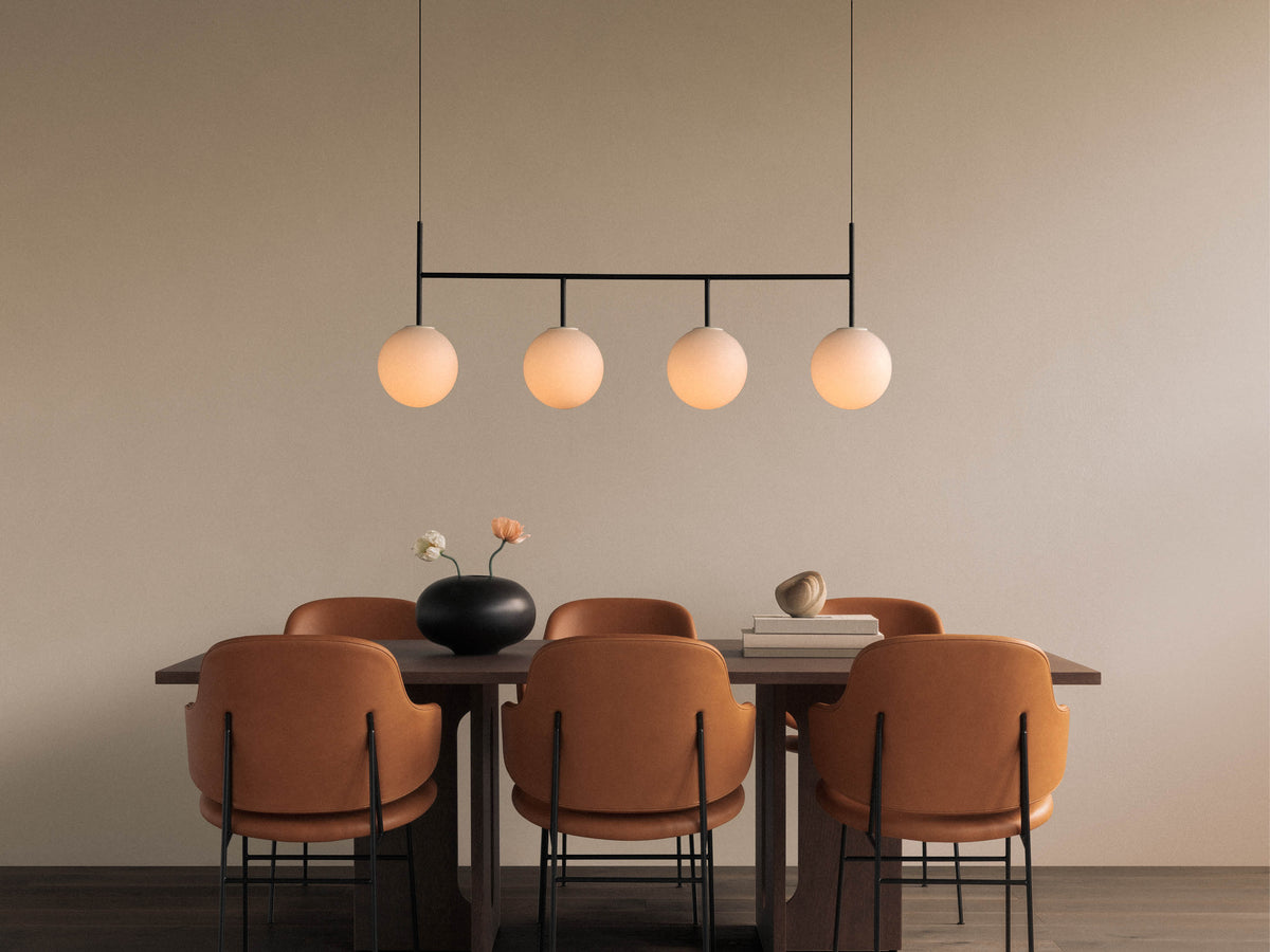 Four-globe pendant light with frosted glass spheres on a black horizontal frame