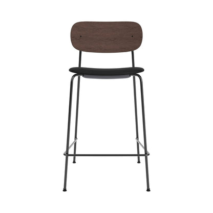 Front view of the Co Counter Chair, Upholstered, with a dark stained oak backrest and black steel frame.