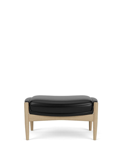The Seal Ottoman in natural oak with dark leather upholstery shown from the front against a white background.