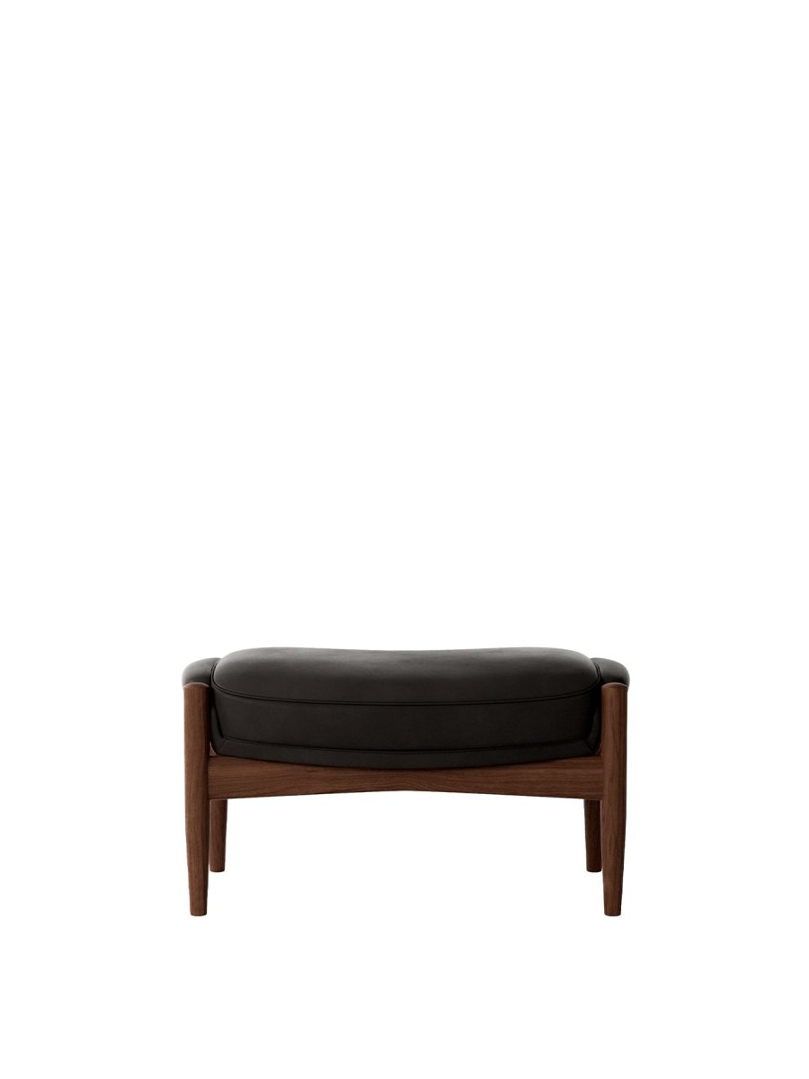 The Seal Ottoman in solid walnut with dark leather upholstery, shown from the front against a white background.