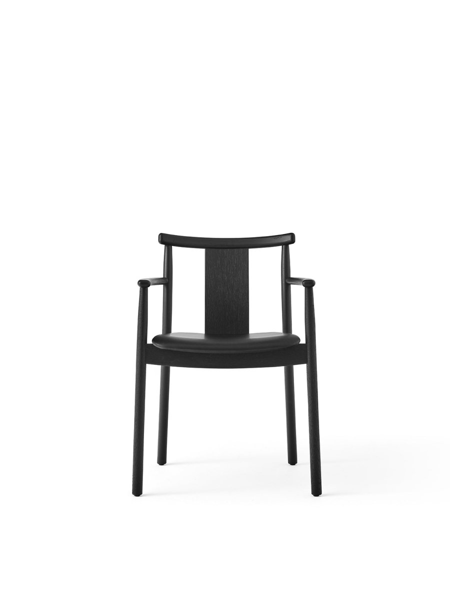 Merkur Dining Chair With Armrests in black stained oak, featuring a curved backrest and a sleek front-facing silhouette.