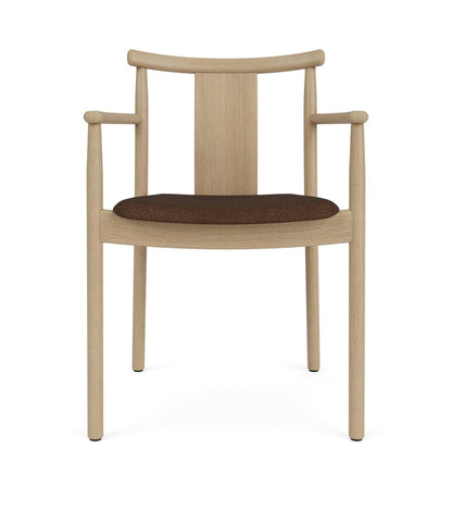 Front view of the Merkur Dining Chair with armrests in natural oak with a dark brown bouclé upholstered seat.
