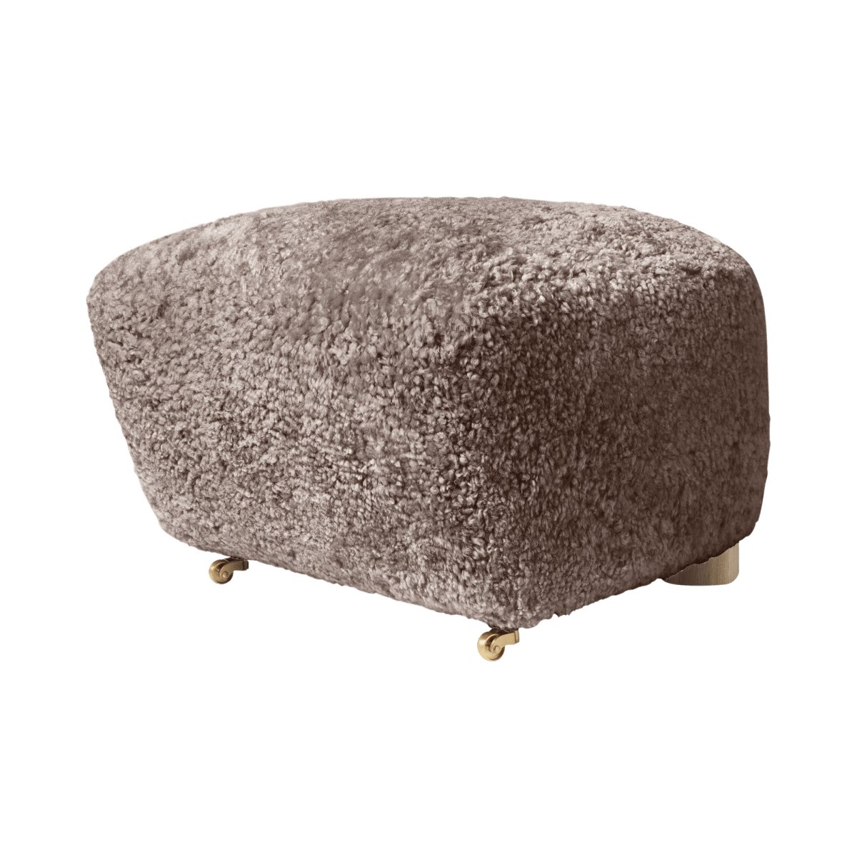 The Tired Man Ottoman upholstered in soft textured sheepskin in a neutral brownish shade, standing on small brass castors.