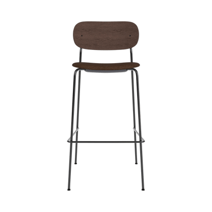Front view of the Co Bar Chair featuring a dark stained oak back, black bouclé seat, and slender black metal frame.