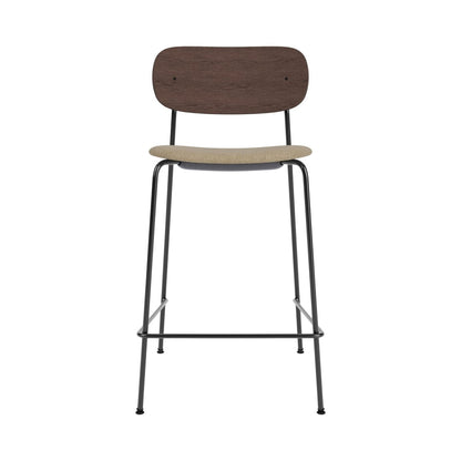 Co Counter Chair featuring a dark stained oak backrest, beige boucle seat, and slender black powder-coated steel frame.