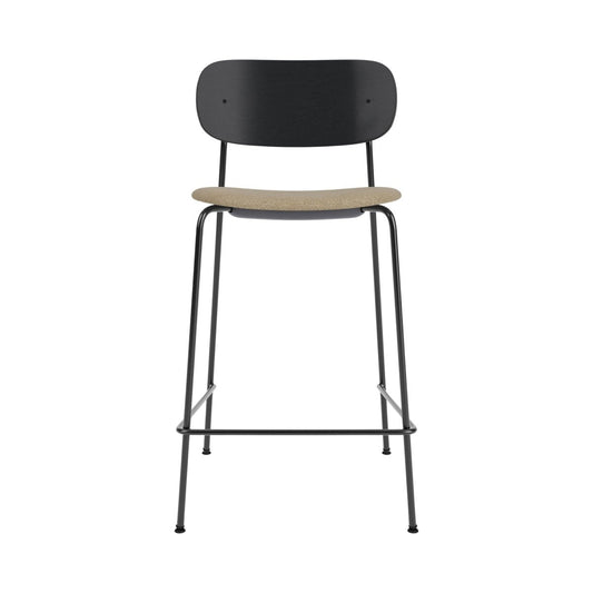 Co Counter Chair featuring a black painted oak back, slender steel frame, and a textured beige bouclé upholstered seat.