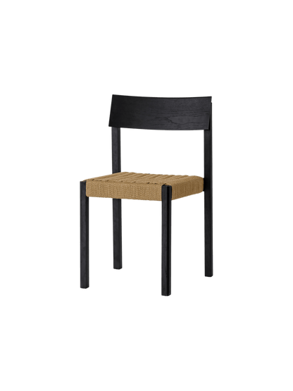 Mauro Dining Chair in black oak with a handwoven natural paper cord seat, shown from a three-quarter angle.