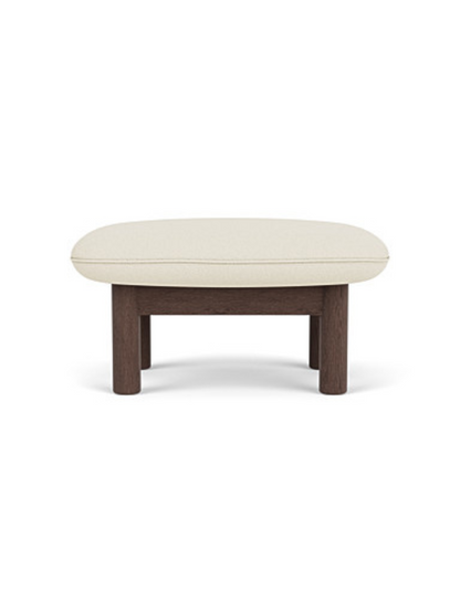 Front-on view of the Brasilia Ottoman, showing its dark wood frame with thick, round legs and a plush, cream-colored cushion
