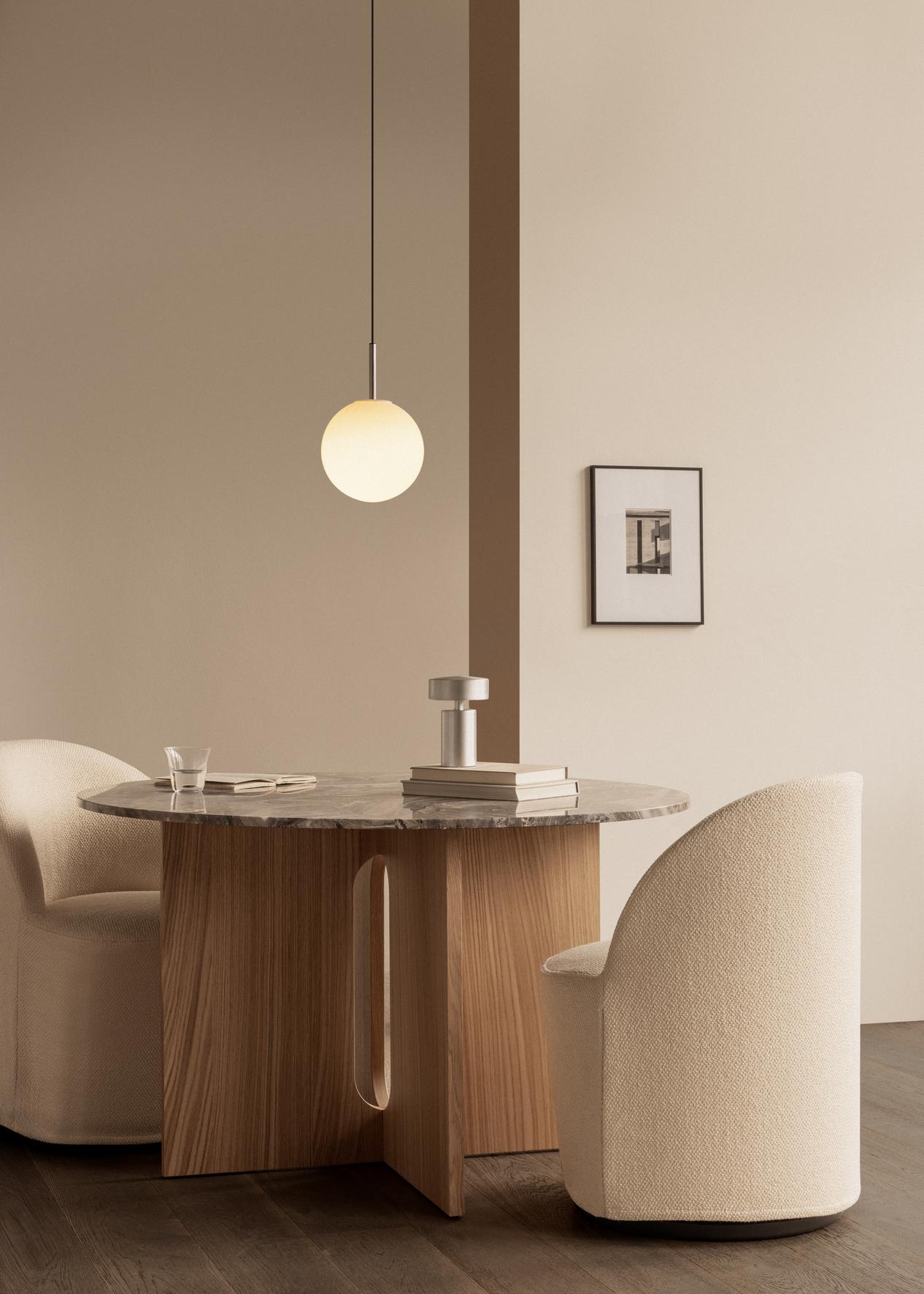 Round marble-top dining table with wooden pedestal, cream upholstered chairs and a hanging frosted glass globe pendant lamp