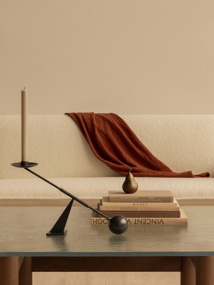 Black Interconnect Candle Holder on glass-topped Brasilia Lounge Table with books and pear. Cream Brasilia Sofa, rust throw.