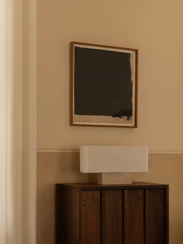 Audo Nonna Table Lamp, Travertine on a slatted wood cabinet, below a