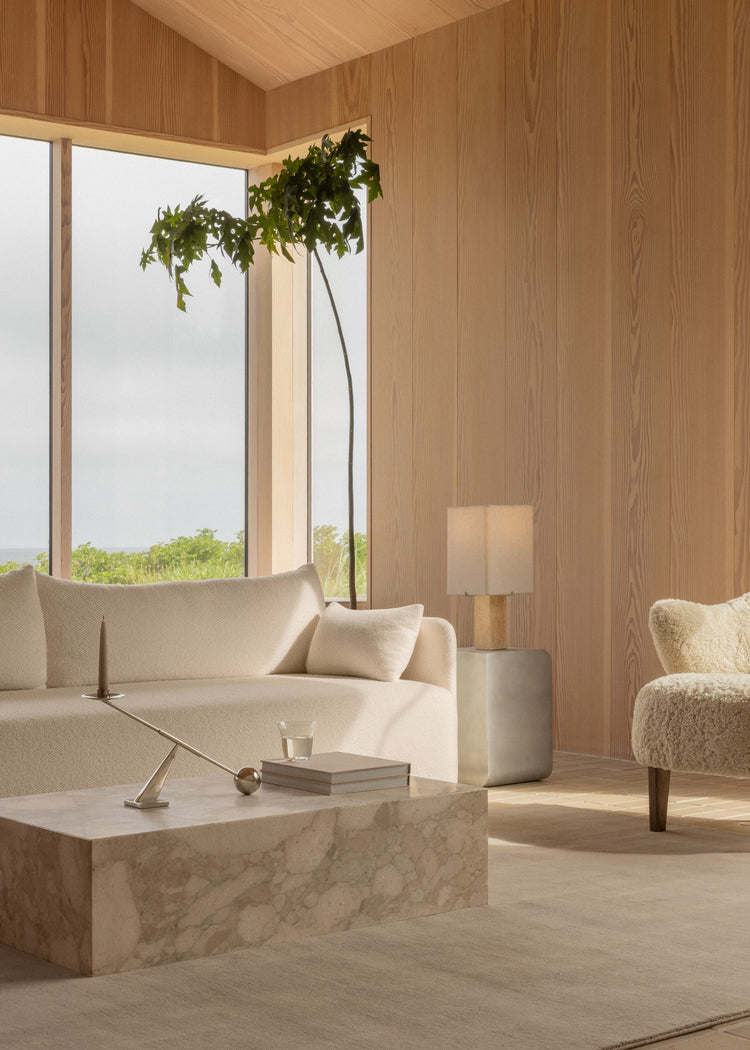 Minimal living room with cream fabric sofa, marble block coffee table, cylindrical lamp on concrete side table and tall