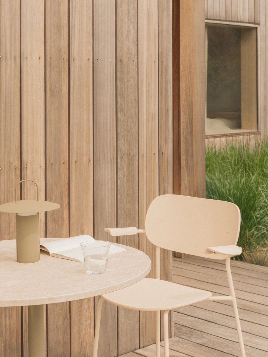 Ivory Co Dining Chair, Outdoor, Nook Dining Table, olive Ray Table Lamp Portable, notebook and water glass on a wooden patio.