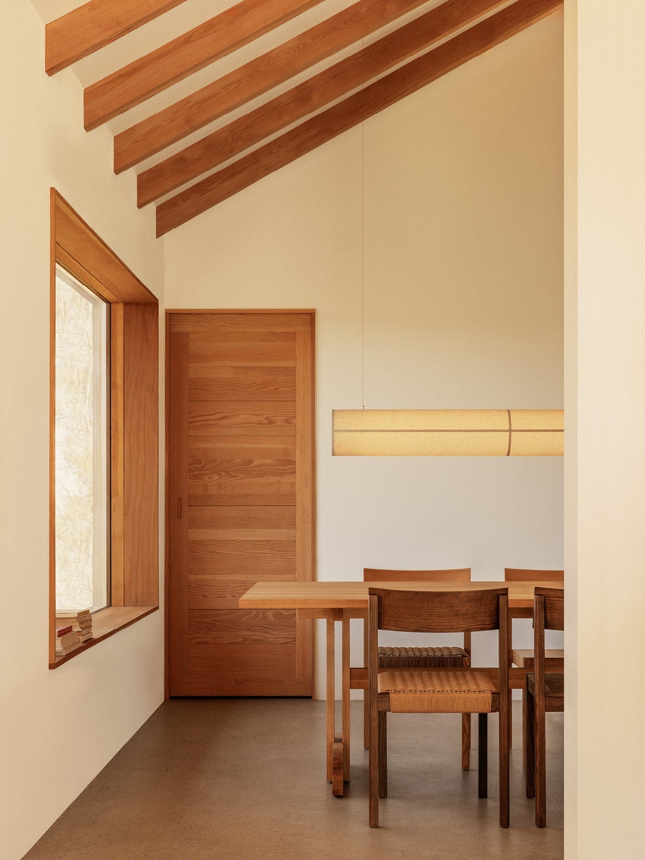 Rectangular Puffin Dining Table and Mauro Dining Chairs with papercord seats beneath a Hashira Linear Pendant Lamp.