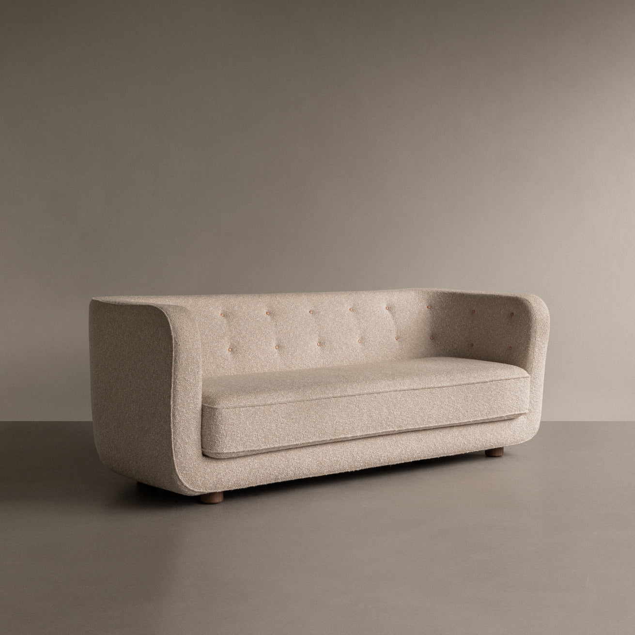 Beige boucle three-seater sofa with rounded arms, button-tufted back and wooden low legs on neutral background