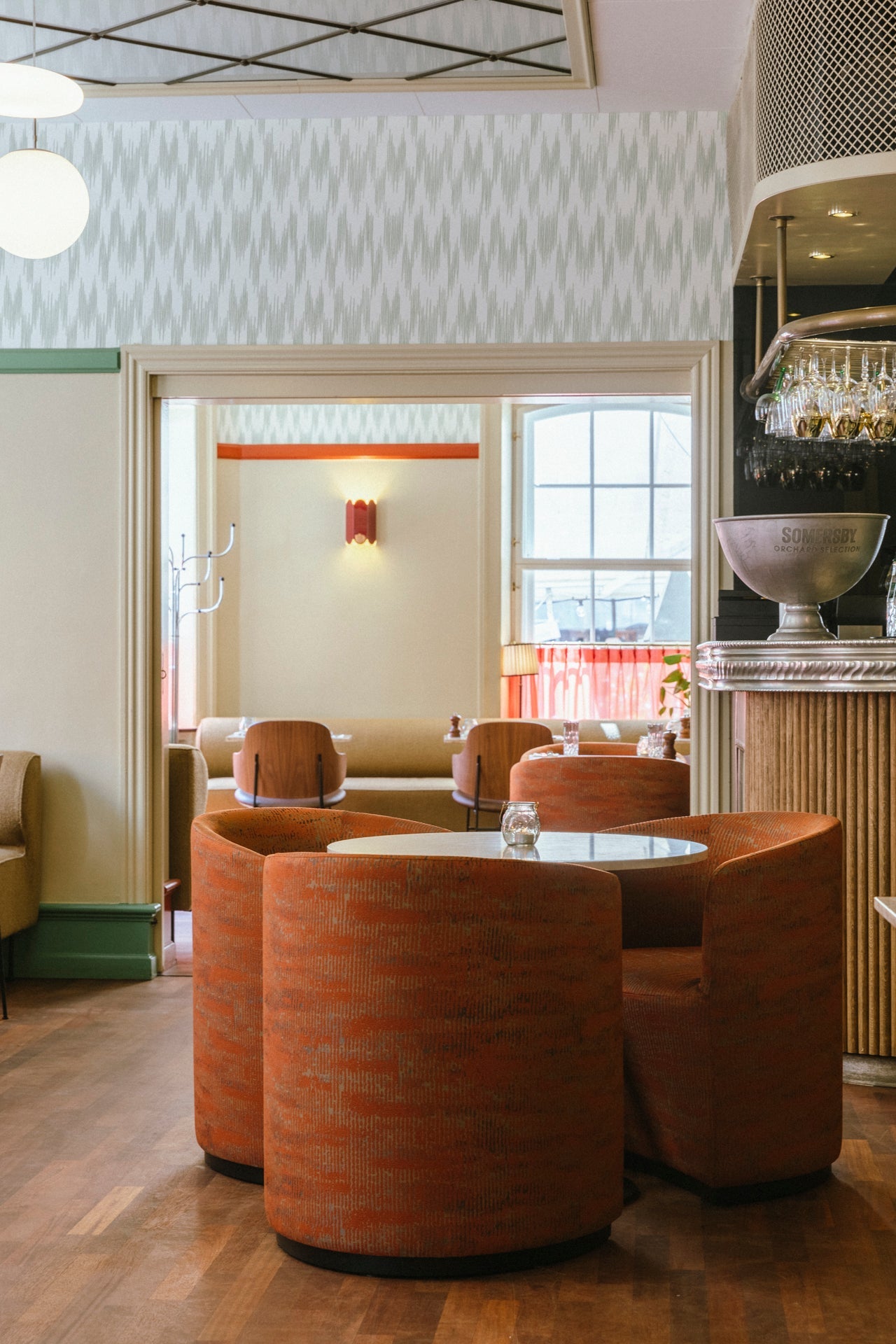 Round orange upholstered booth seating around a small white table in a retro-styled café interior.