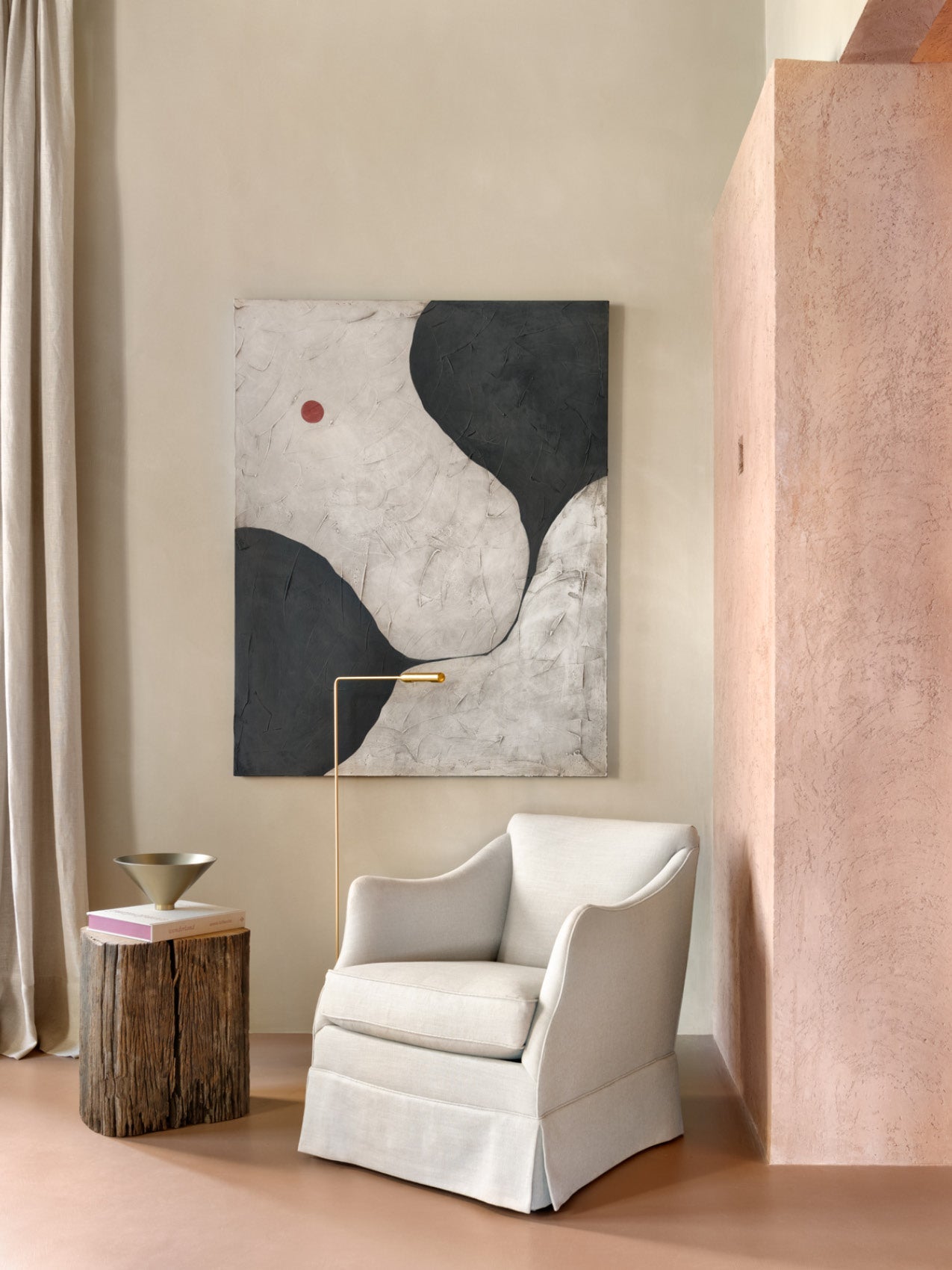 Neutral-toned lounge chair with soft linen upholstery beside a wooden stump side table, gold floor lamp and abstract