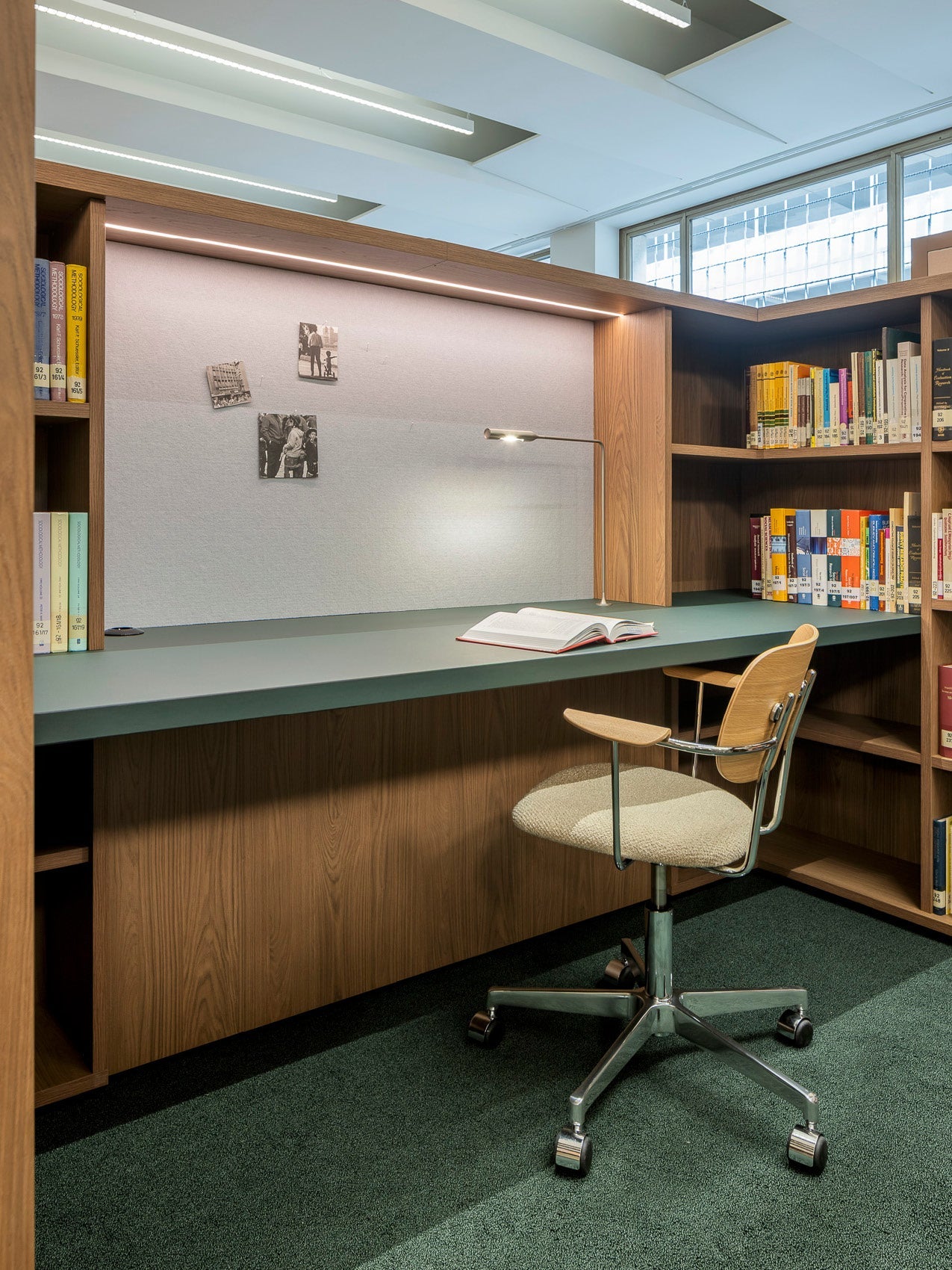 Wooden built-in study desk with green laminate surface, overhead LED strip, adjustable metal desk lamp, bookshelf and swivel