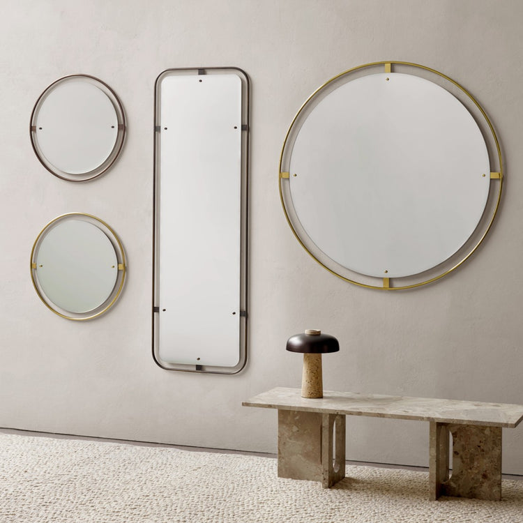 Minimalist wall arrangement of four mirrors with thin brass and dark metal frames over a stone bench and mushroom lamp