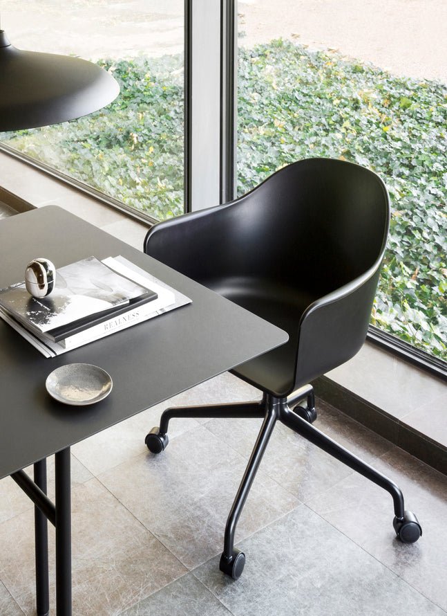 Black Harbour Arm Chair with a star base and casters at a minimalist desk, featuring an organic, modern silhouette.