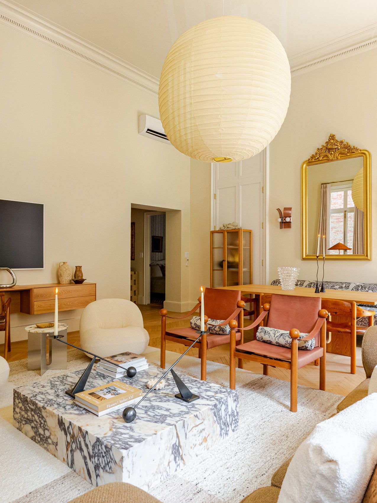 Scandinavian living room with large round paper pendant light, marble coffee table, leather sling chairs and neutral tones