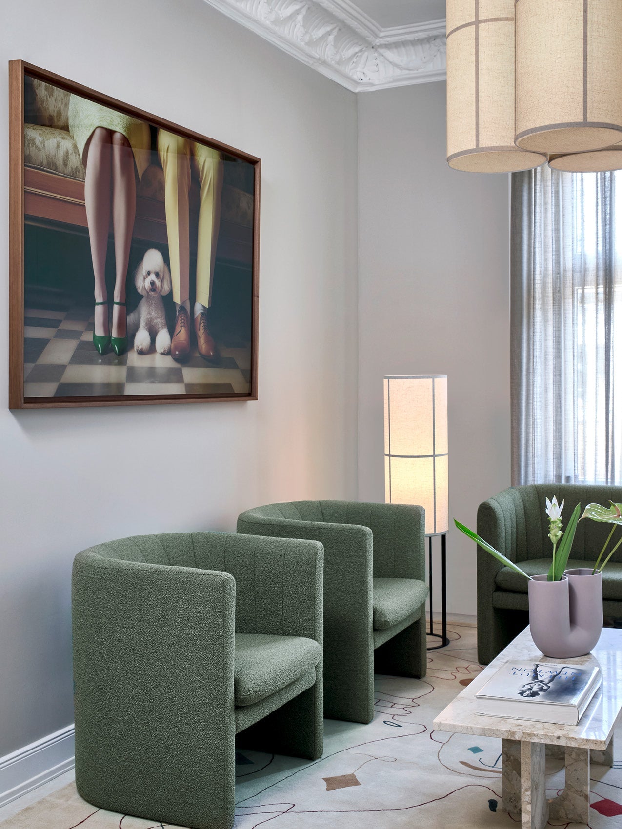 Modern lounge with three curved sage-green upholstered armchairs, marble coffee table, tall fabric floor lamp and framed art.