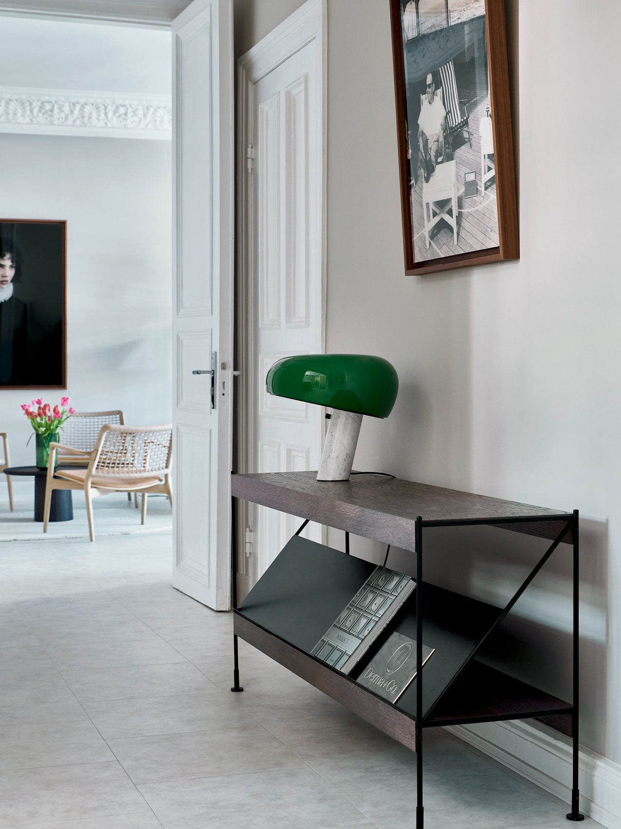 Green glass mushroom table lamp with white marble stem on dark wood and black metal console in bright Scandinavian hallway