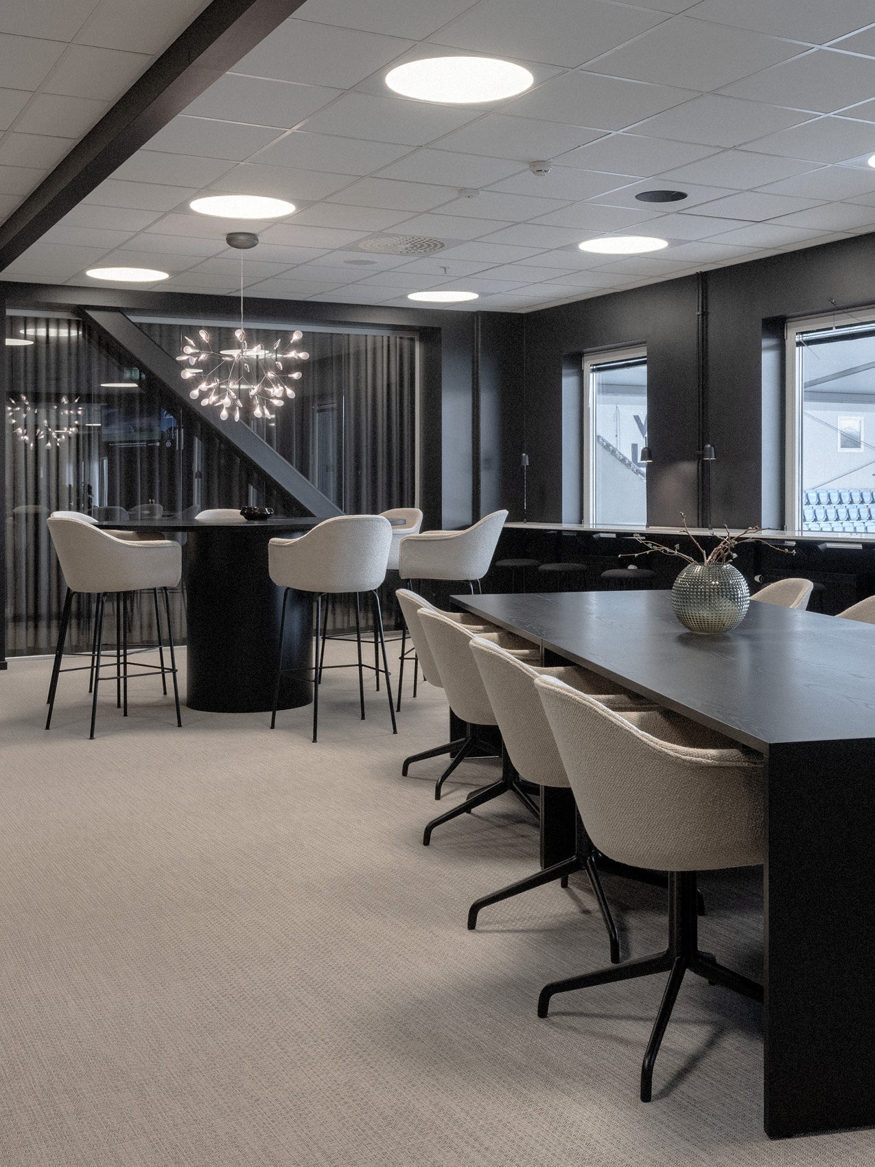 Modern lounge with black tables, cream upholstered swivel bar and dining chairs, round ceiling lights and decorative pendant