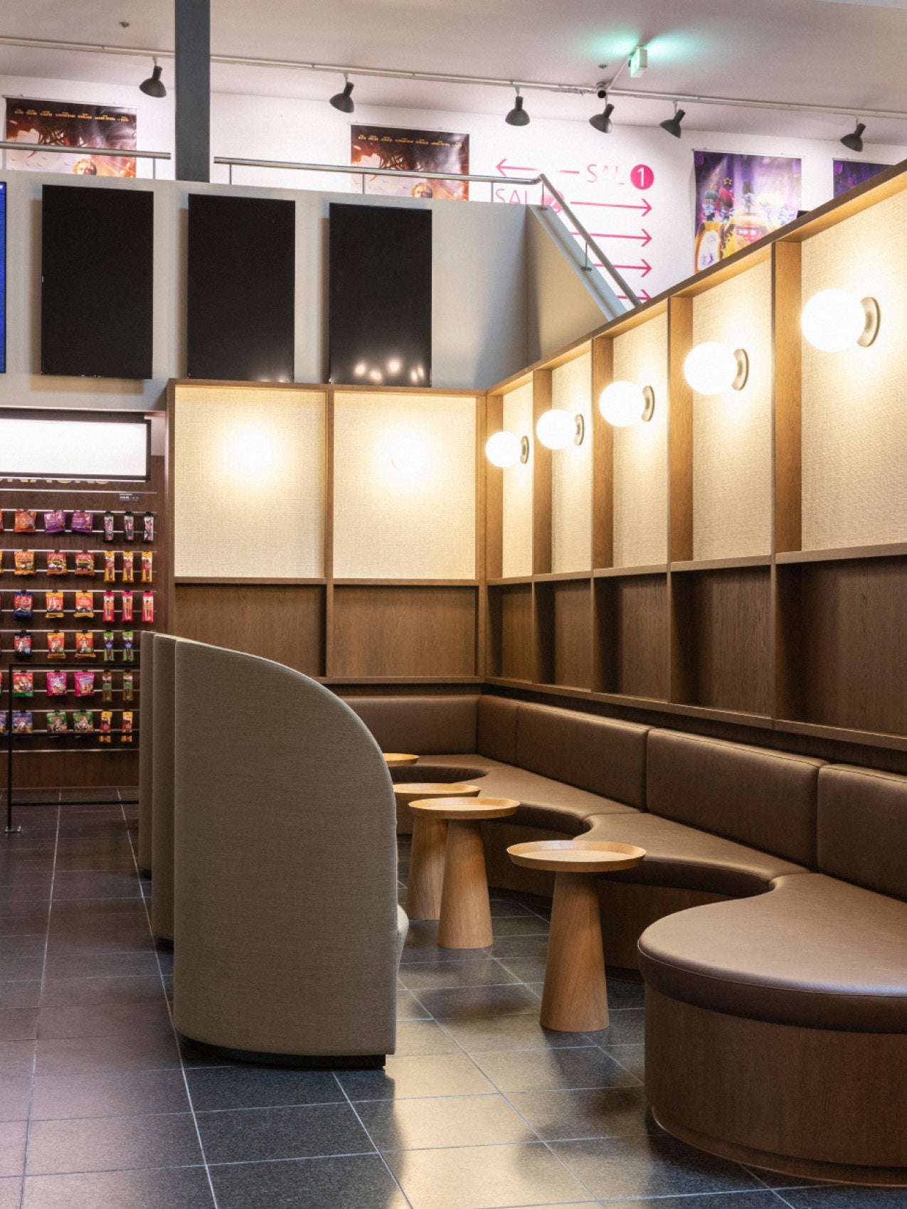 Modern seating corner with curved brown leather banquette, round wooden stools, beige upholstered privacy screens and