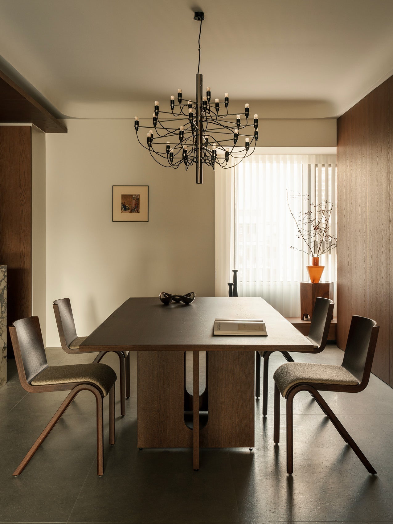 Minimal dining room with dark wood rectangular table, four curved wood chairs with upholstered seats and a black multi-arm