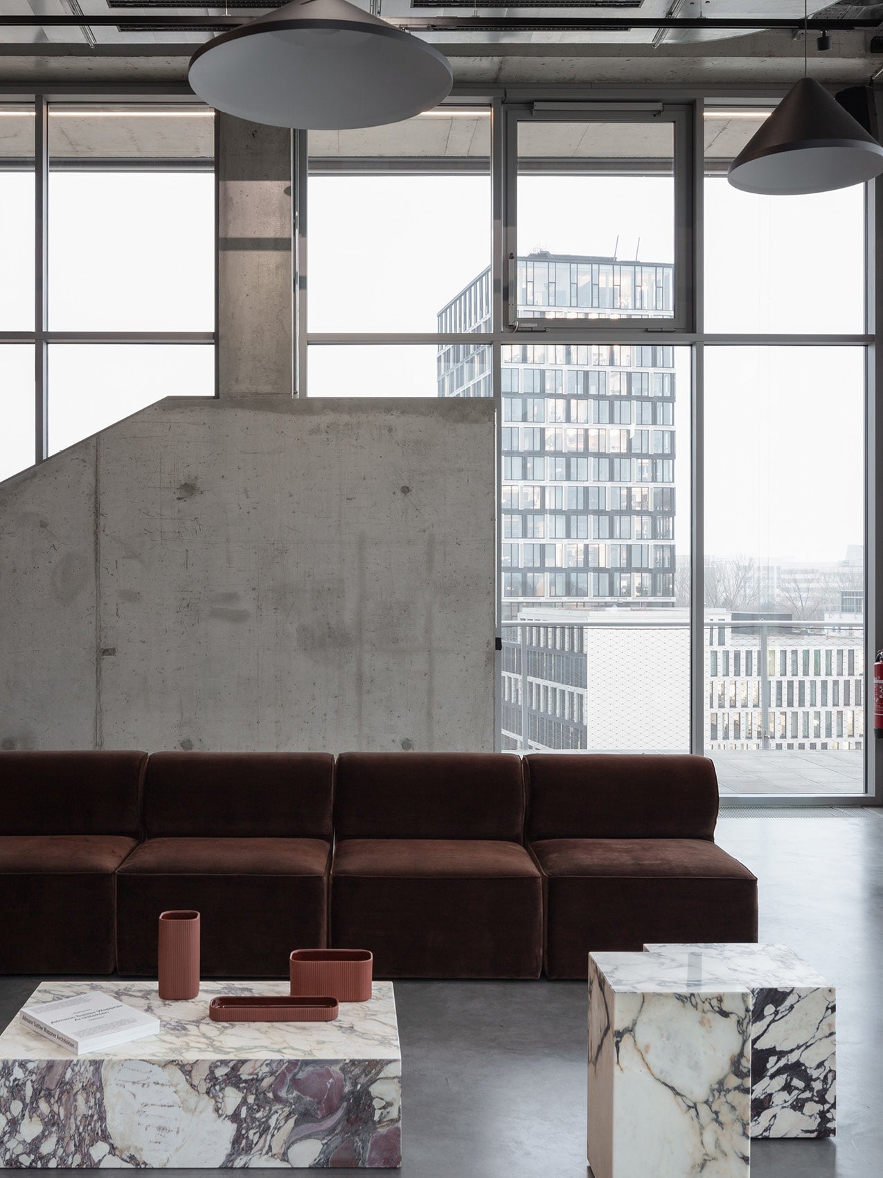 Minimalist living room with dark brown velvet modular sofa, marble cube coffee tables and terracotta accessories by