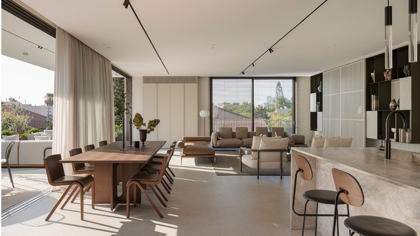 Open-plan living and dining area with walnut dining table, curved wooden chairs, beige sofas, marble kitchen island and