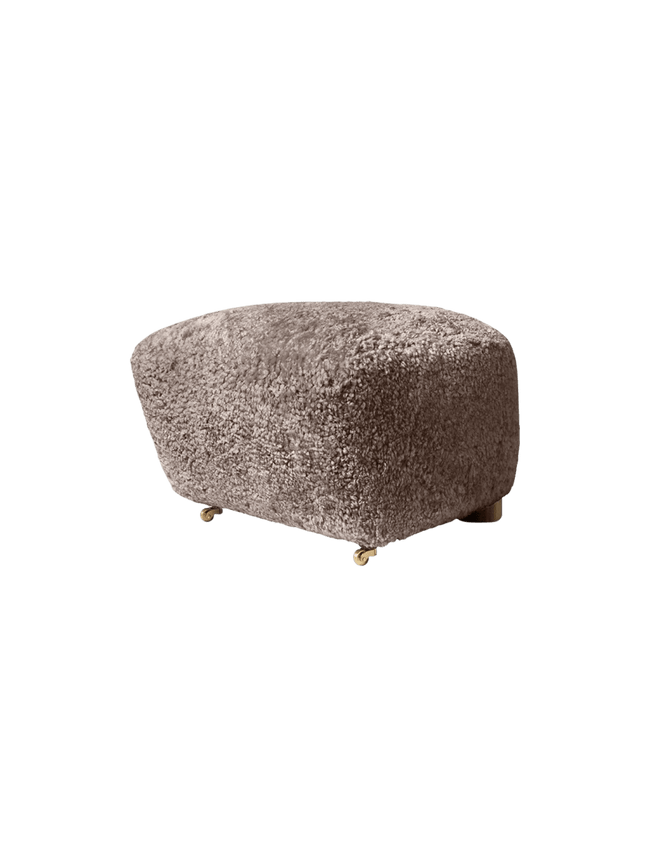 The Tired Man Ottoman upholstered in sheepskin Sahara, shown from the side with small brass castors.