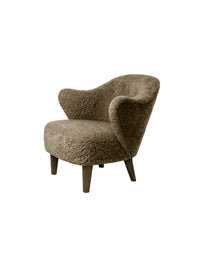 A three-quarter view of the Ingeborg Lounge Chair upholstered in a textured, brown sheepskin with four dark-stained oak legs.