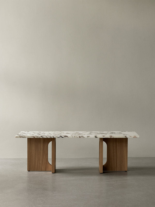 A frontal shot of the Androgyne Lounge Table, featuring a rectangular marble top on a natural oak base with arched cutouts.